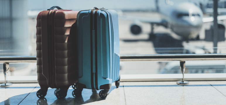 Image of the lower half of a person pulling luggage in an airport-type setting