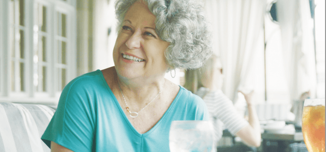 Image of a happy woman sitting at a table eating a meal