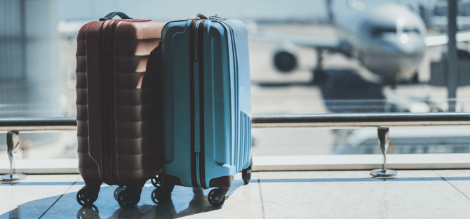 Image of the lower half of a person pulling luggage in an airport-type setting