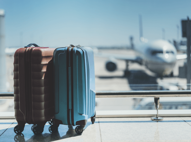 Image of the lower half of a person pulling luggage in an airport-type setting