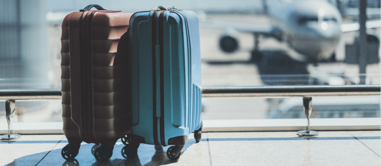 Image of the lower half of a person pulling luggage in an airport-type setting